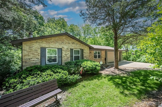 back of property featuring brick siding, an attached garage, a yard, and driveway