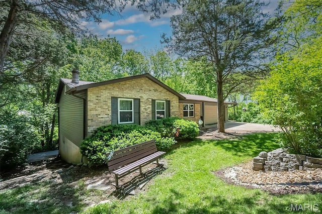 back of property featuring brick siding, a yard, and an attached garage