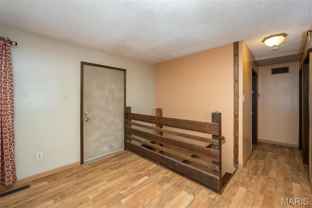 unfurnished room with light wood finished floors, a textured ceiling, and baseboards