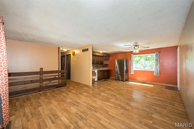 unfurnished living room featuring light wood finished floors, a ceiling fan, and a textured ceiling