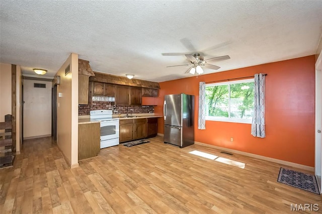 kitchen featuring white range with electric stovetop, freestanding refrigerator, a sink, light countertops, and ceiling fan