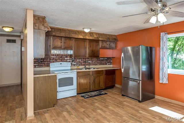 kitchen featuring freestanding refrigerator, white electric stove, a sink, a textured ceiling, and light countertops