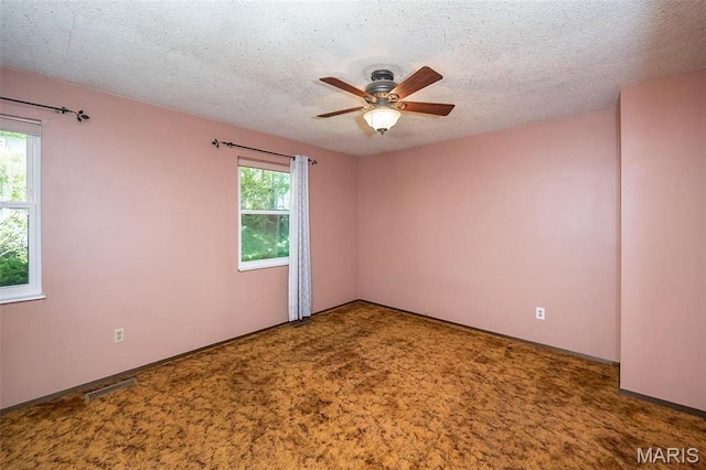 carpeted empty room with a ceiling fan and a textured ceiling