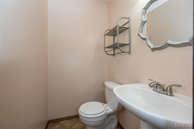 half bathroom with toilet, a sink, and baseboards
