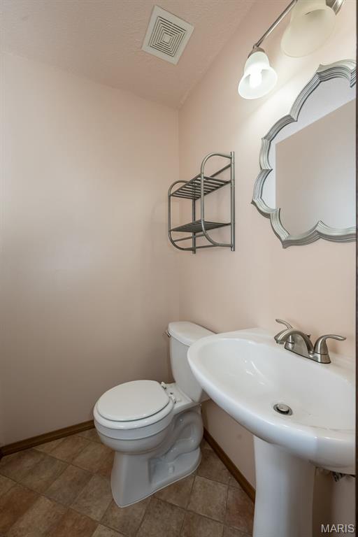 bathroom with toilet, baseboards, and a sink