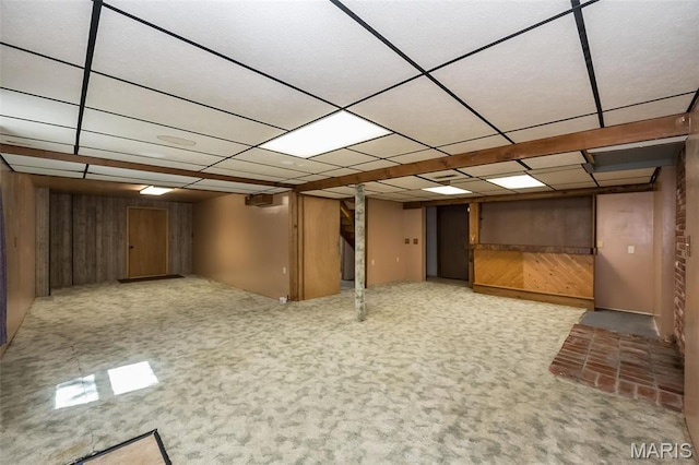 finished below grade area with a drop ceiling and wood walls