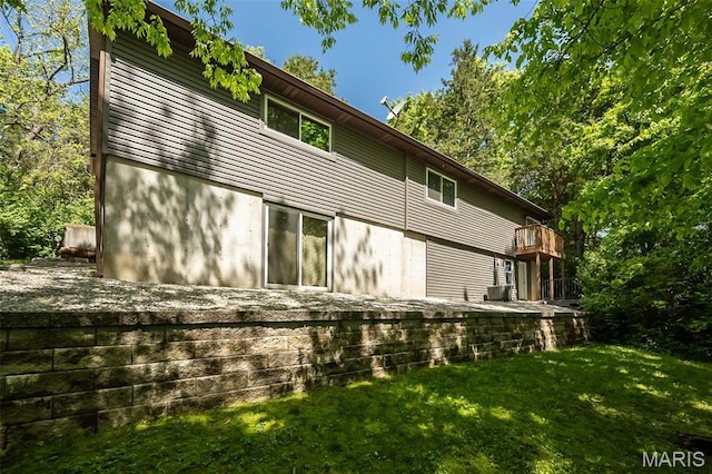 back of house with central air condition unit and a lawn