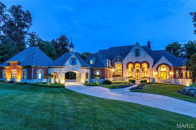 french country style house with a chimney, a front yard, and stone siding