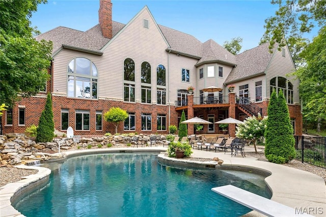 swimming pool with a patio area, fence, and a diving board