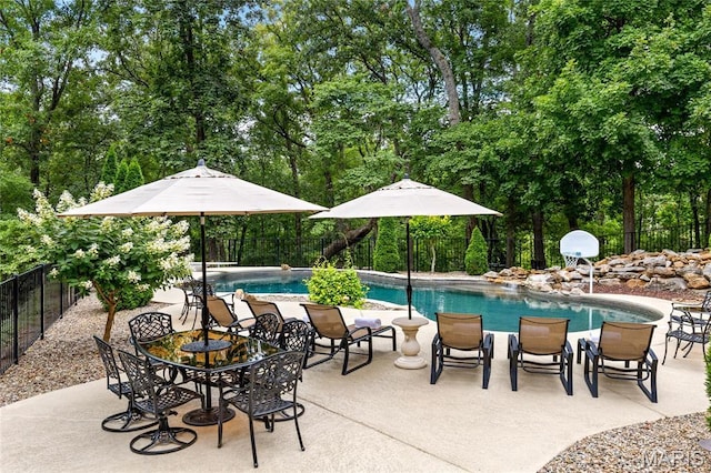view of pool featuring a fenced backyard, view of wooded area, and a patio