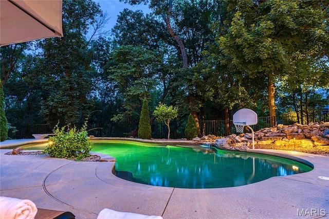 swimming pool featuring fence, a patio area, and view of scattered trees