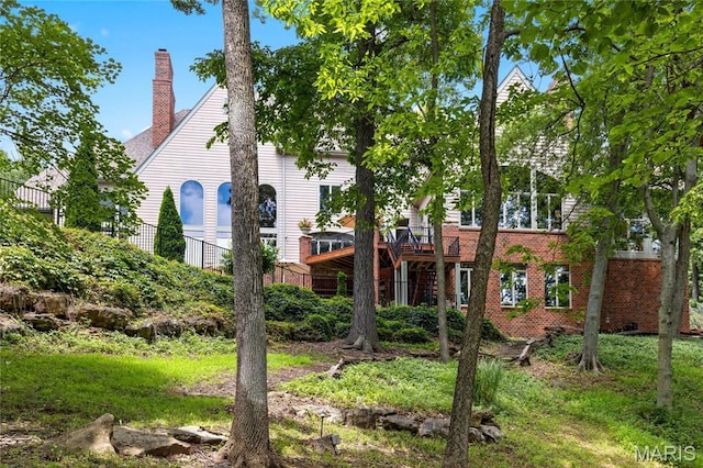 back of house with a chimney, a wooden deck, and brick siding
