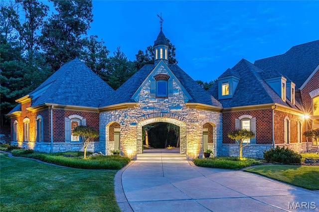 view of front of property with stone siding, a front yard, and brick siding