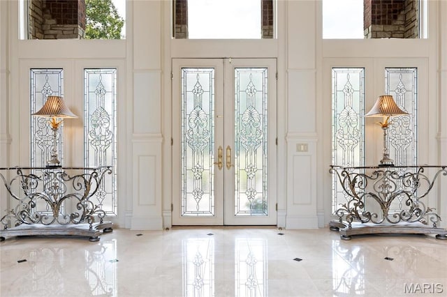 entryway with french doors, a chandelier, and a high ceiling