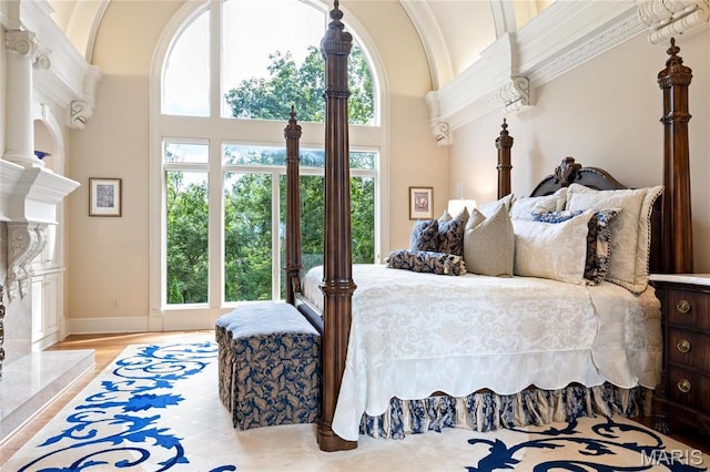 bedroom featuring a towering ceiling, wood finished floors, and baseboards
