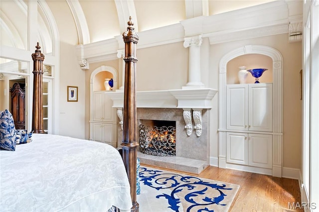 bedroom featuring a fireplace, light wood-style flooring, and ornamental molding