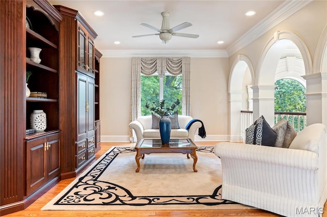 living area featuring a ceiling fan, light wood-style flooring, ornamental molding, baseboards, and recessed lighting