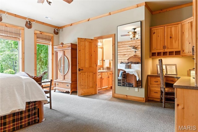 bedroom with light carpet, a desk, and ensuite bath