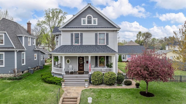victorian house featuring covered porch, a front yard, and central AC