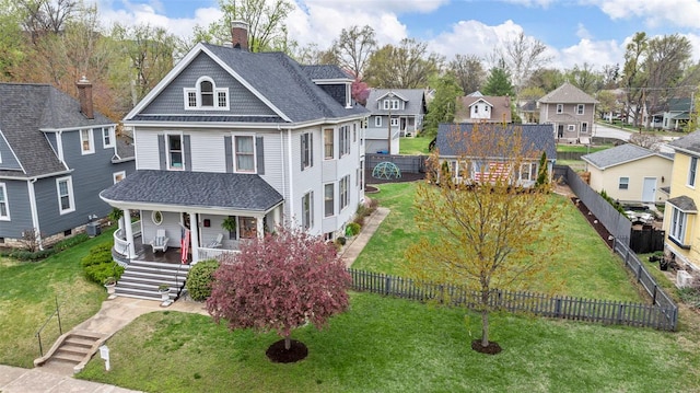victorian home featuring covered porch, a residential view, a chimney, and roof with shingles