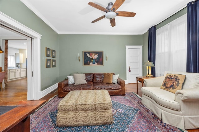 living area featuring a ceiling fan, wood finished floors, ornamental molding, and baseboards