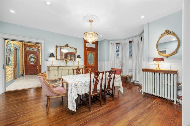 dining space featuring radiator, a chandelier, wood finished floors, a wainscoted wall, and recessed lighting