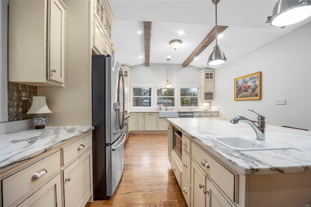 kitchen with appliances with stainless steel finishes, a sink, a kitchen island with sink, light wood-style flooring, and glass insert cabinets