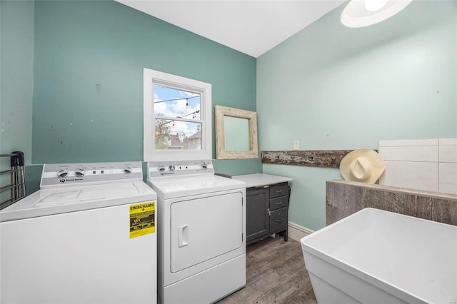 washroom featuring washing machine and clothes dryer, wood finished floors, and cabinet space