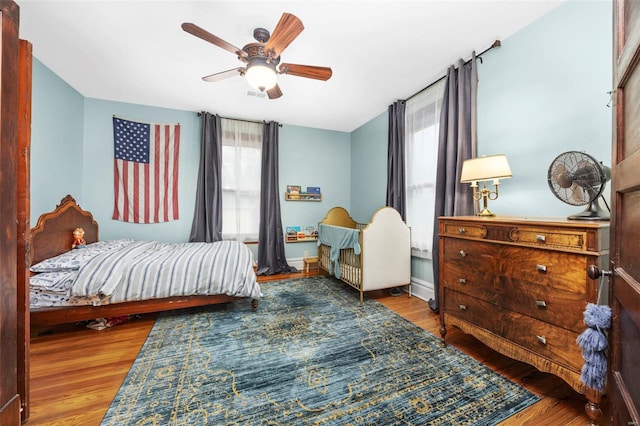bedroom with multiple windows, wood finished floors, and ceiling fan