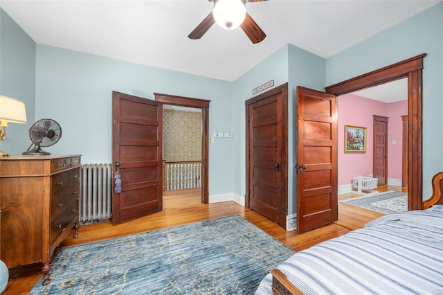 bedroom featuring radiator heating unit, light wood-style flooring, baseboards, and ceiling fan