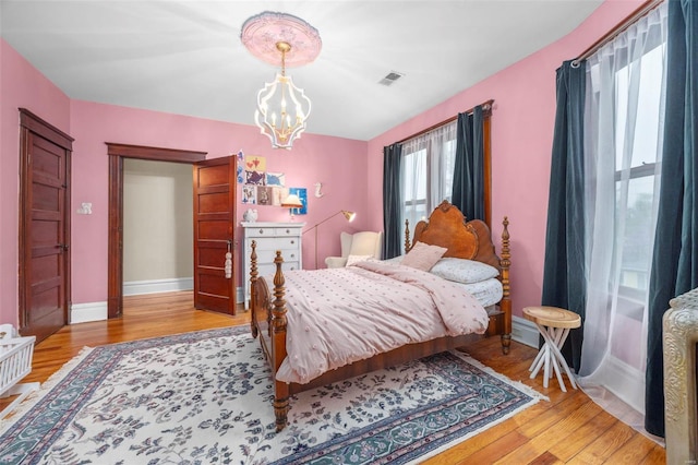 bedroom featuring a chandelier, light wood-style flooring, and baseboards