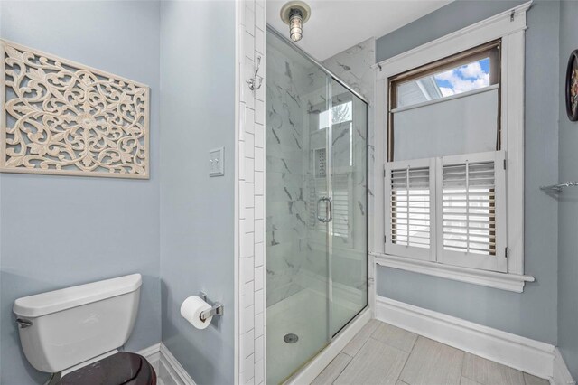 bathroom with a stall shower, baseboards, and toilet