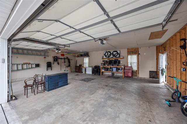 garage with a workshop area, wooden walls, and a garage door opener