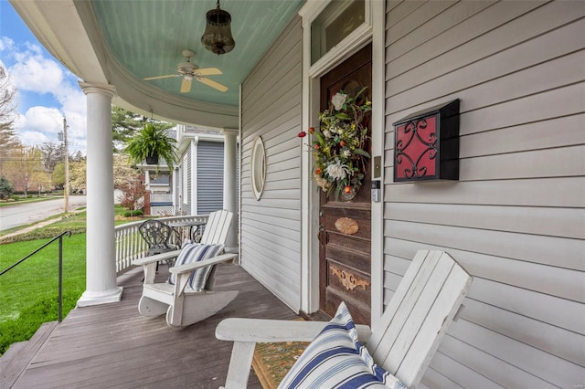 wooden terrace featuring a porch, ceiling fan, and a lawn