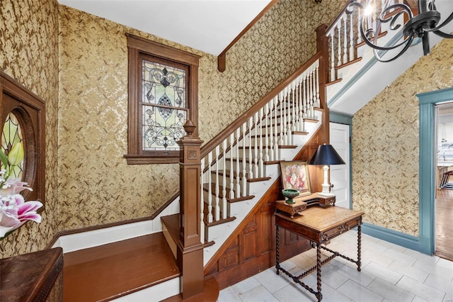 stairway with wallpapered walls, tile patterned flooring, and a chandelier