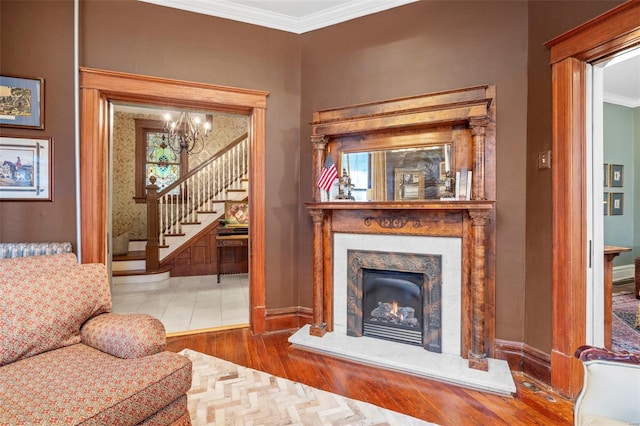 living area featuring baseboards, stairway, ornamental molding, a chandelier, and a high end fireplace