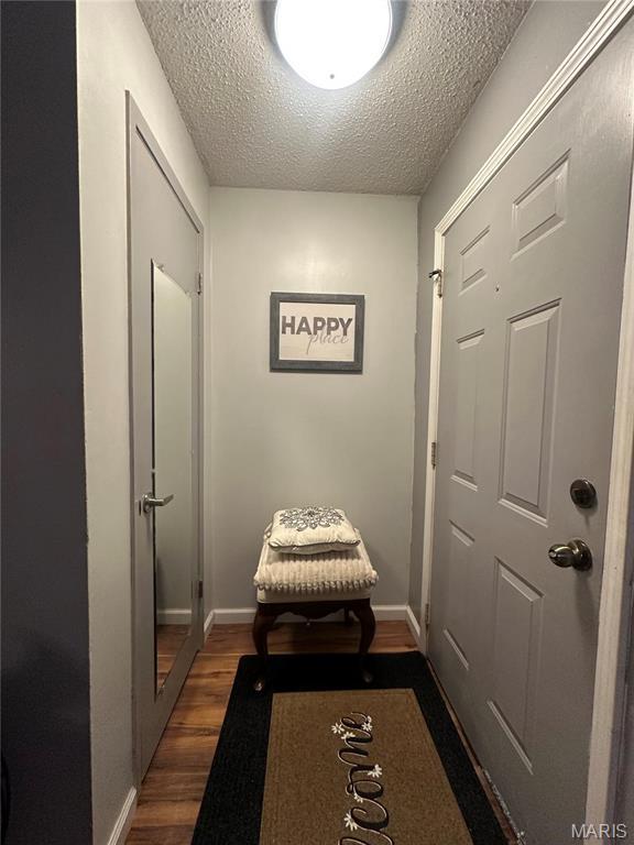 doorway to outside with dark wood finished floors, a textured ceiling, and baseboards