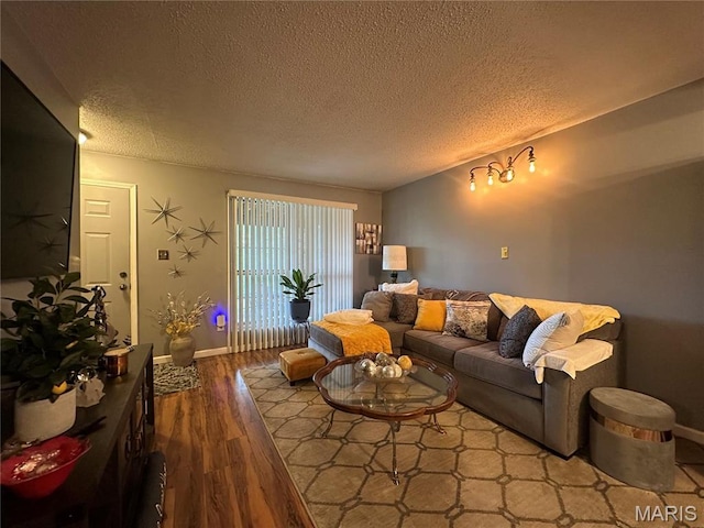 living area featuring a textured ceiling, wood finished floors, and baseboards