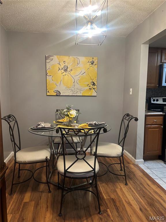 dining area with a textured ceiling, light wood-type flooring, and baseboards