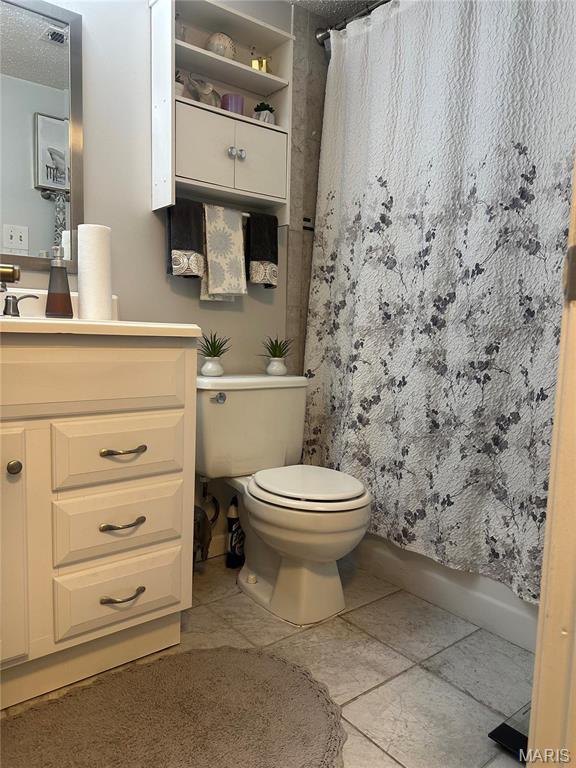 full bathroom with toilet, vanity, and tile patterned floors
