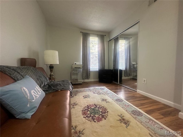 bedroom with wood finished floors, a closet, and baseboards