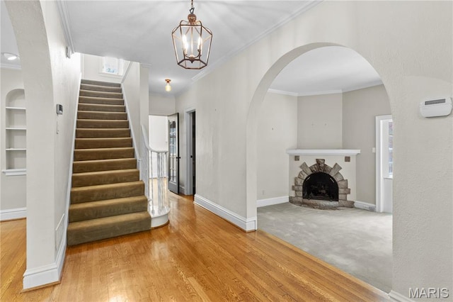 46 Broadview Dr, Clayton, MO 63105 - entryway featuring stairs, crown molding, wood finished floors, a fireplace with raised hearth, and arched walkways