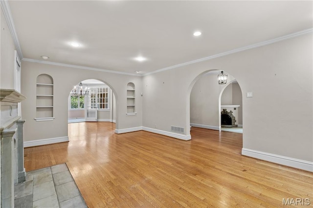 46 Broadview Dr, Clayton, MO 63105 - unfurnished living room with a fireplace, arched walkways, built in shelves, a chandelier, and crown molding