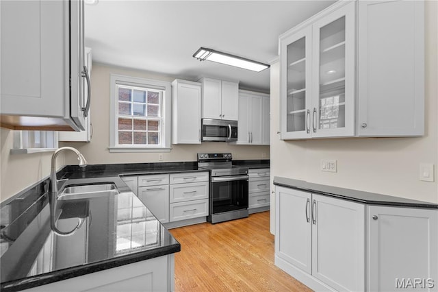 46 Broadview Dr, Clayton, MO 63105 - kitchen featuring stainless steel appliances, white cabinets, light wood-style flooring, glass insert cabinets, and dark countertops