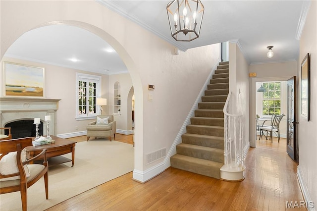 46 Broadview Dr, Clayton, MO 63105 - staircase featuring wood finished floors, arched walkways, crown molding, and a fireplace