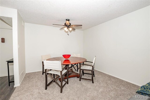 carpeted dining room with ceiling fan, a textured ceiling, and baseboards