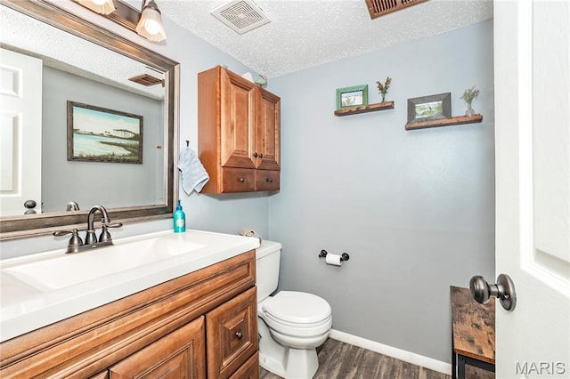 bathroom with wood finished floors, toilet, vanity, a textured ceiling, and baseboards