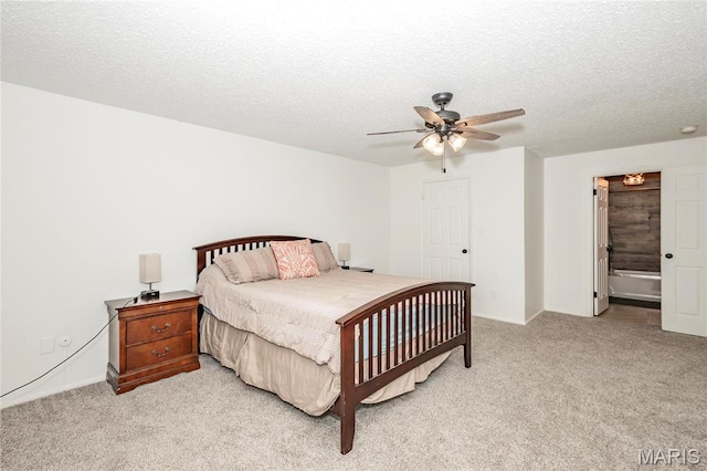 bedroom with light colored carpet, a textured ceiling, ceiling fan, and ensuite bath
