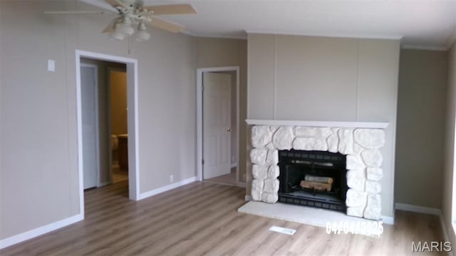 610 E Green St, Mascoutah, IL 62258 - unfurnished living room with wood finished floors, ceiling fan, crown molding, baseboards, and a stone fireplace