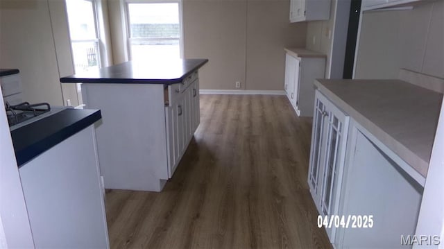 610 E Green St, Mascoutah, IL 62258 - kitchen with light wood-type flooring, white cabinetry, a kitchen island, and baseboards